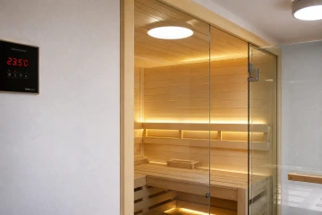 Prosklená interiérová sauna Cuvier z osiky s celoprosklenou čelní stěnou a moderním LED podsvícením